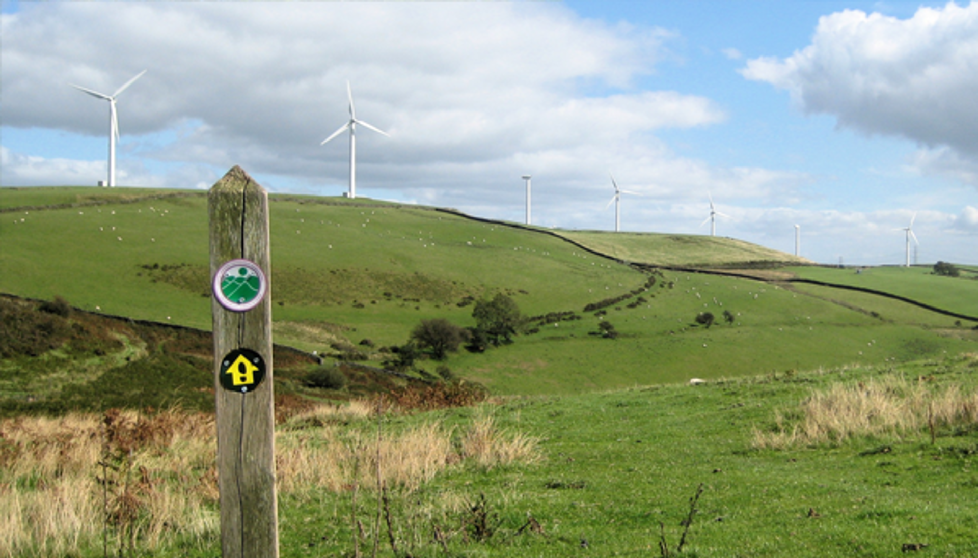 Marciwr ffordd ger tyrbinau gwynt ar ochr y bryn