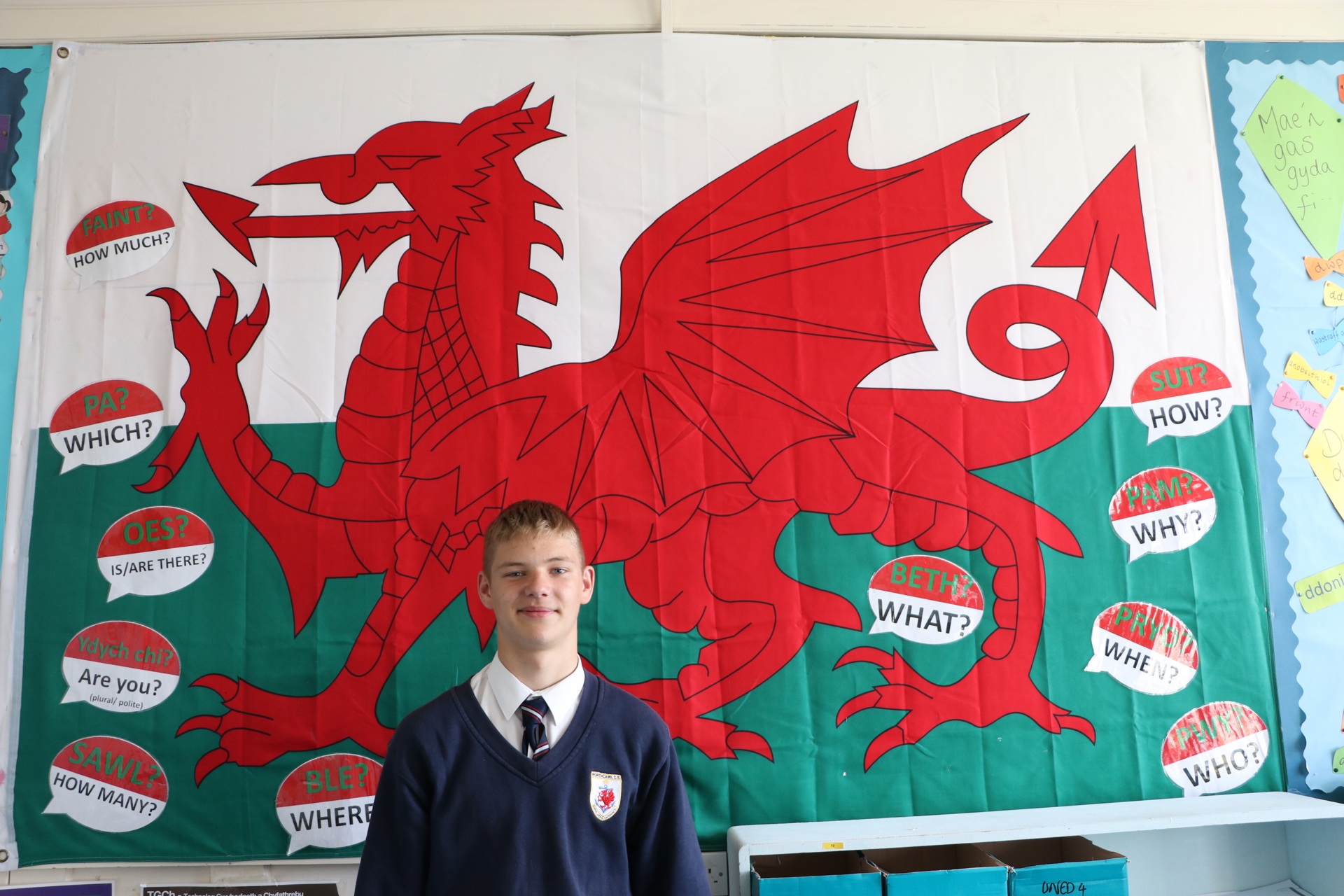 Disgybl porthcawl o'r Wcrain o flaen baner Cymru.