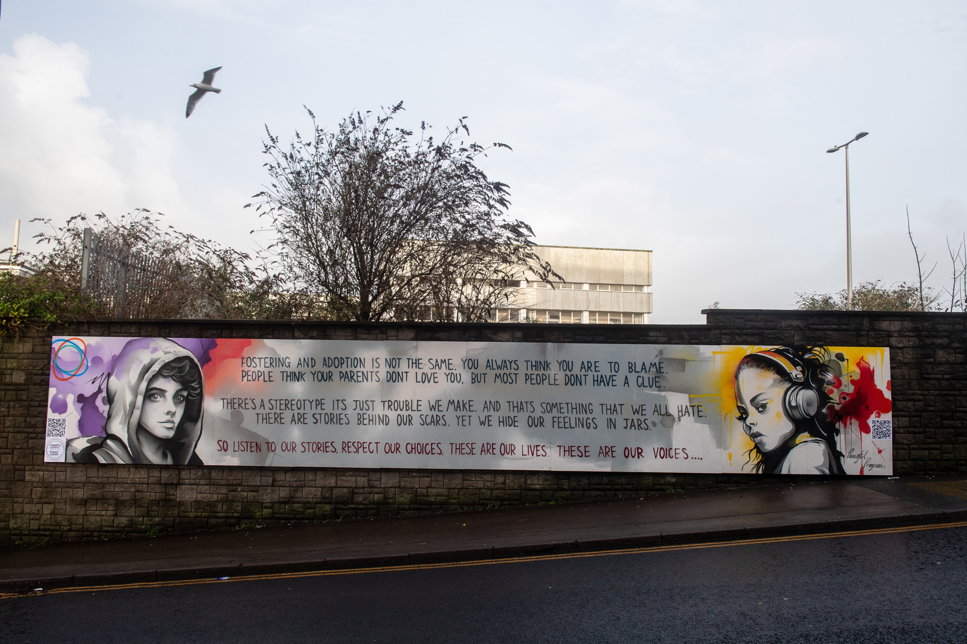 Cerdd mewn murlun ar Stryd Bracla, Pen-y-bont ar Ogwr. ae'r gerdd yn dweud: Fostering and Adoption is not the same, you always think you are to blame. People think your parents don't love you, but most people don't have a clue. There's a stereotype it's just trouble we make, and that's something that we all hate. There are stories behind our scars, yet we hide our feelings in jars. So listen to out stories, respect our choices, these are our lives, these are our voices.